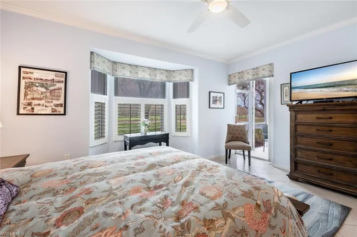 Bedroom featuring light tile patterned flooring, ceiling fan, crown molding, and access to exterior