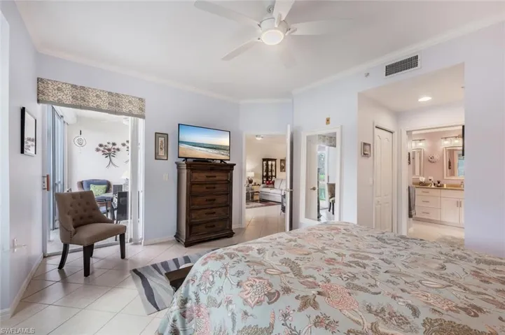 Tiled bedroom with ceiling fan, ensuite bath, and ornamental molding