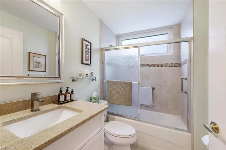 Full bathroom featuring toilet, combined bath / shower with glass door, and vanity