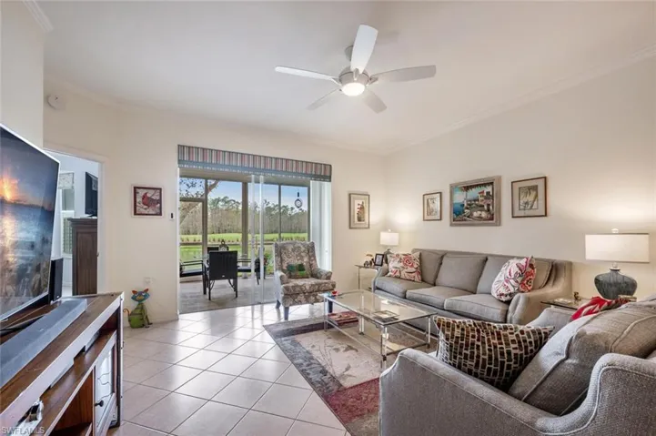 Living room featuring ornamental molding, ceiling fan, and light tile patterned floors