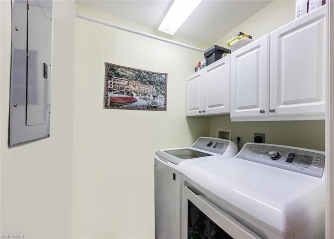 Laundry area featuring cabinets, washer and dryer, and electric panel