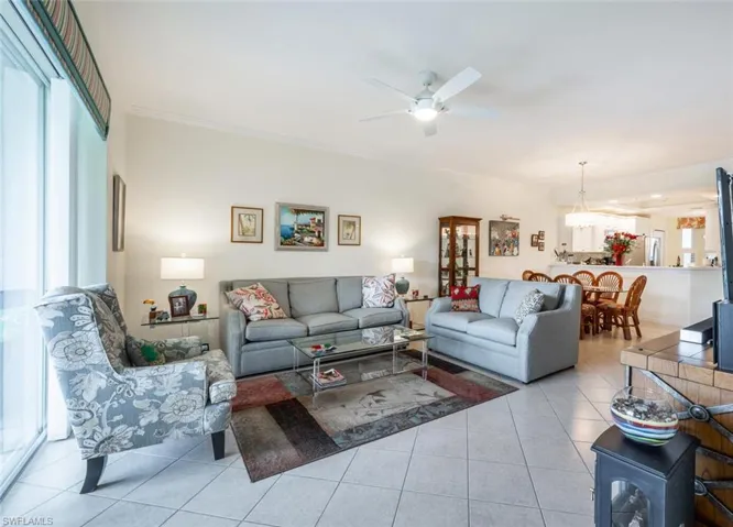 Living room with crown molding, ceiling fan, and light tile patterned floors