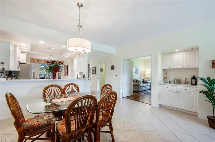 Dining space with a tray ceiling, crown molding, and light tile patterned flooring