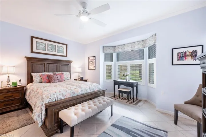 Bedroom featuring light tile patterned floors, ceiling fan, and ornamental molding