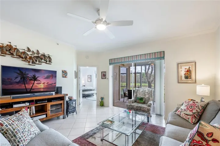 Living room with crown molding, ceiling fan, and light tile patterned floors