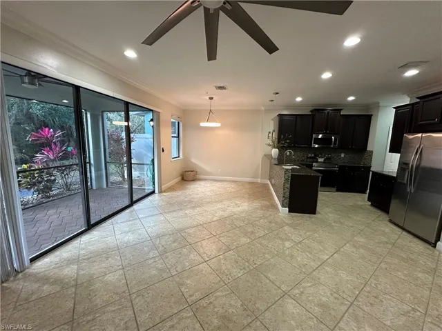 Kitchen featuring dark cabinets, appliances with stainless steel finishes, a peninsula, dark stone counters, and recessed lighting