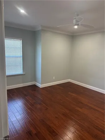 Unfurnished room featuring crown molding, dark wood-type flooring, and ceiling fan