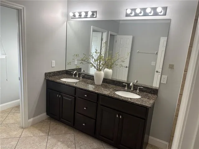 Full bath featuring double vanity and light tile patterned flooring