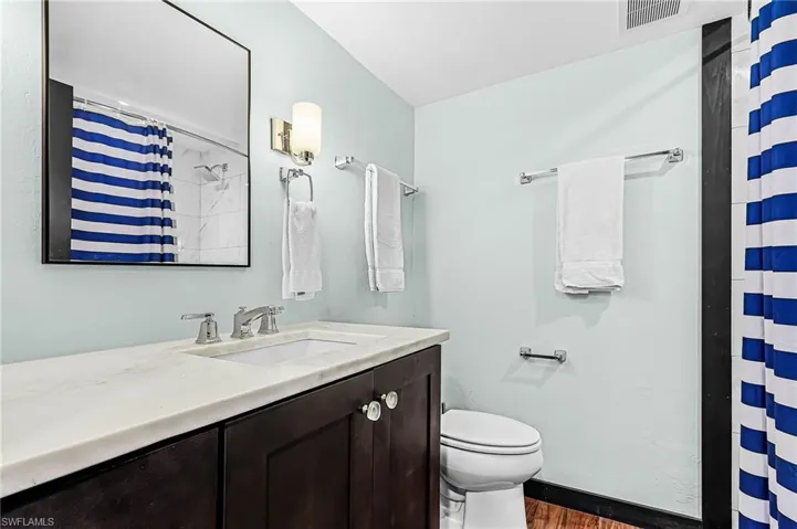 Bathroom featuring a shower, vanity, and dark wood finished floors