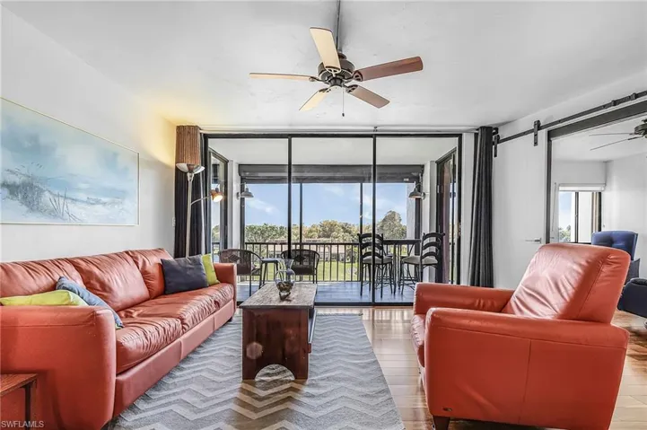 Living room with expansive windows, a ceiling fan, and wood finished floors