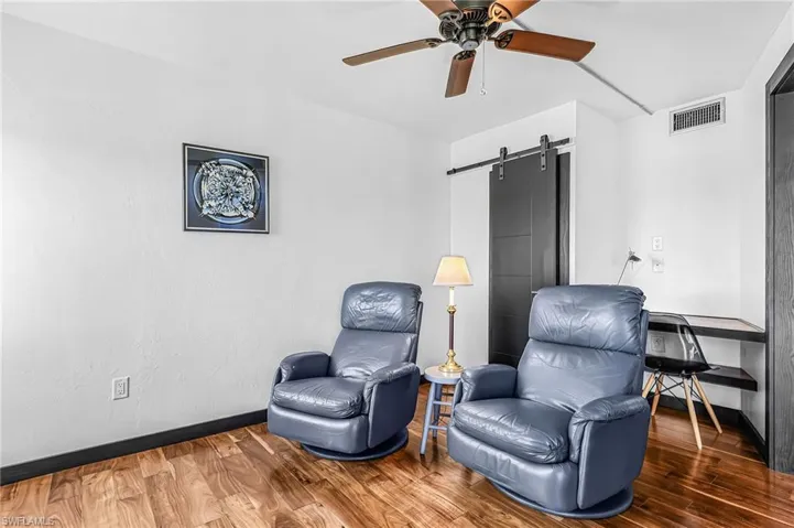 3rd bedroom or sitting room/office, with a sliding door, wood finished floors, and a ceiling fan