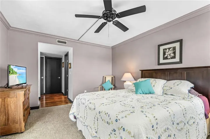 Carpeted bedroom with ornamental molding and a ceiling fan