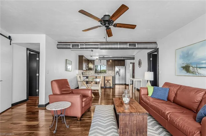 Living room featuring a barn door, wood-style flooring, and a ceiling fan