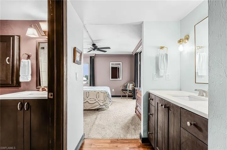 Primary Bathroom with two vanities, ensuite bathroom, light wood-type flooring, carpet in bedroom
