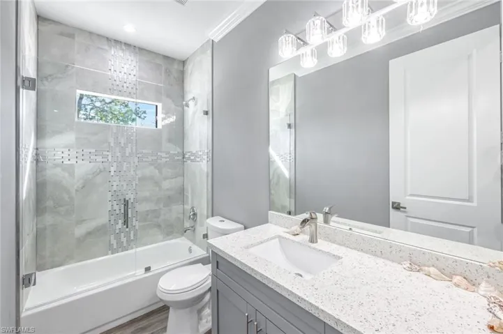Full bathroom with vanity, shower / bath combination with glass door, recessed lighting, and ornamental molding