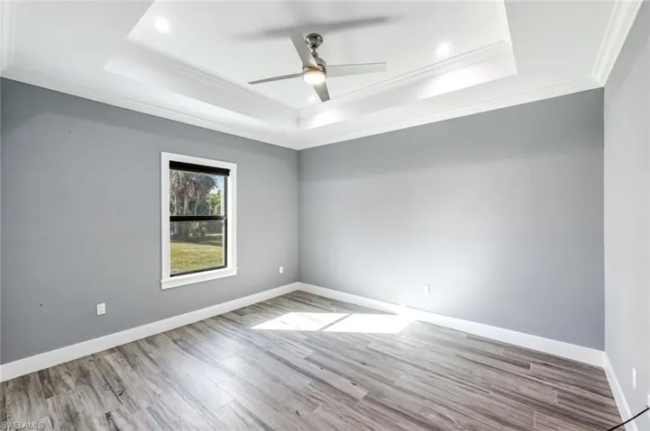 Spare room featuring a ceiling fan, light wood-type flooring, and ornamental molding