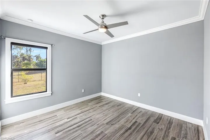 Spare room featuring ornamental molding, light wood finished floors, and a ceiling fan