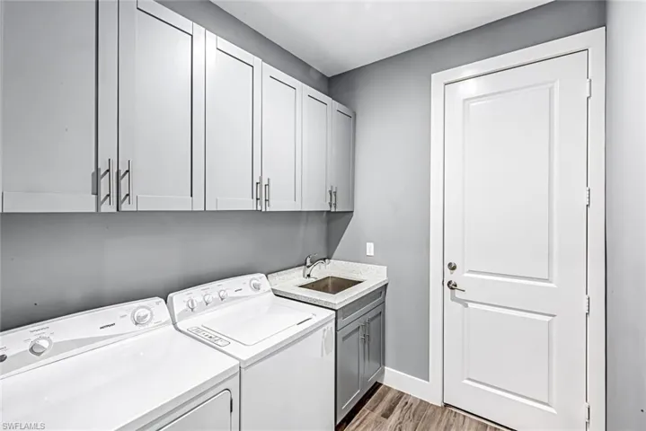 Laundry area with light wood-style flooring, independent washer and dryer, and cabinet space