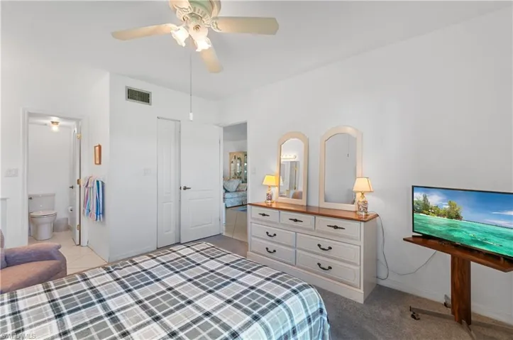Bedroom with ceiling fan, connected bathroom, a closet, and tile patterned floors