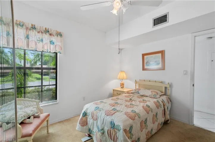 Carpeted bedroom with ceiling fan and multiple windows