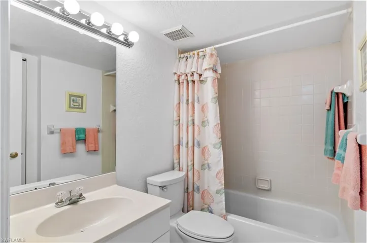 Full bathroom featuring a textured ceiling, toilet, vanity, and shower / bath combo
