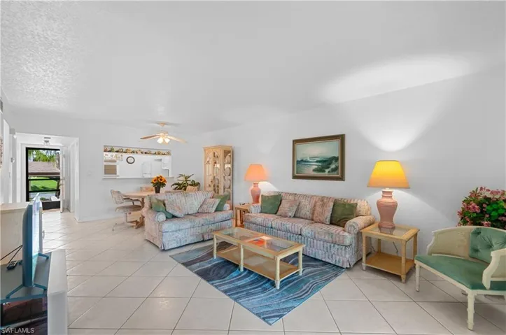 Tiled living room with ceiling fan and a textured ceiling