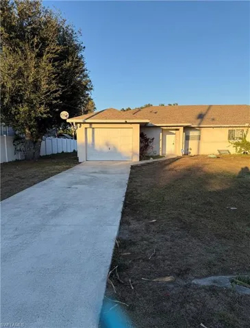 View of front of property with driveway, stucco siding, and an attached garage