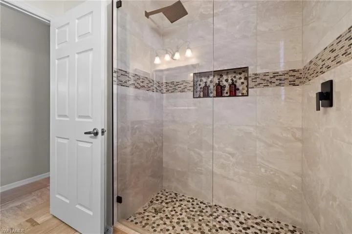 Full bath featuring a shower stall and baseboards