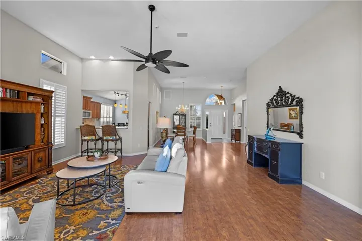 Living area featuring dark wood-style flooring, ceiling fan, and a chandelier