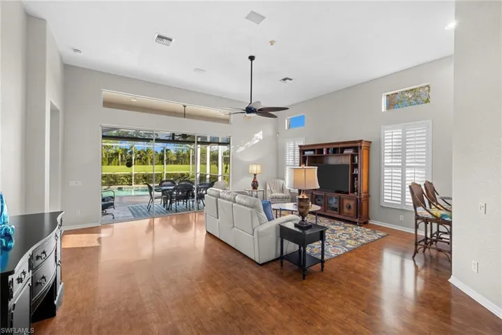 Living room with a sunroom, wood finished floors, and a ceiling fan