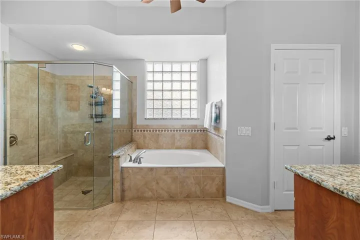 Full bath with vanity, a shower stall, a bath, a ceiling fan, and light tile patterned floors
