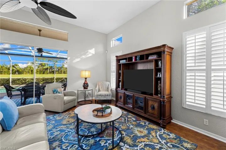 Living room featuring a sunroom, wood finished floors, a ceiling fan, and a textured wall