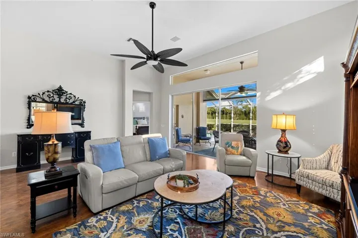 Living room featuring dark wood-style floors, a sunroom, and ceiling fan
