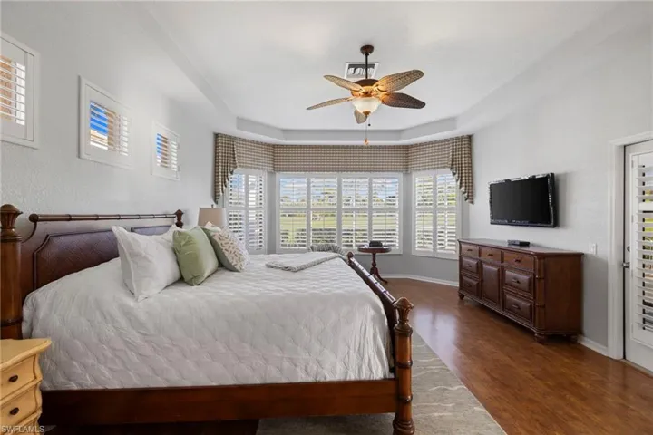 Bedroom featuring dark wood-style floors, a tray ceiling, and a ceiling fan