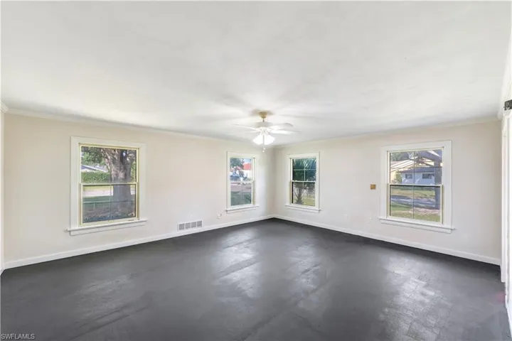 Empty room with a wealth of natural light, ornamental molding, and ceiling fan