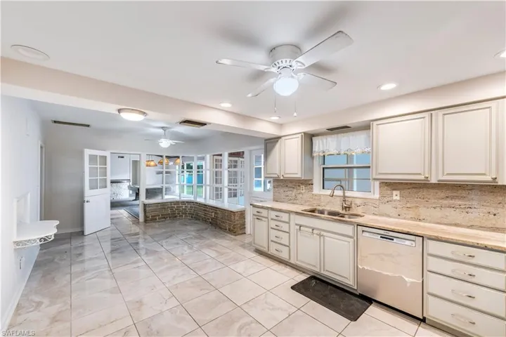 Kitchen featuring dishwasher, sink, ceiling fan, and backsplash