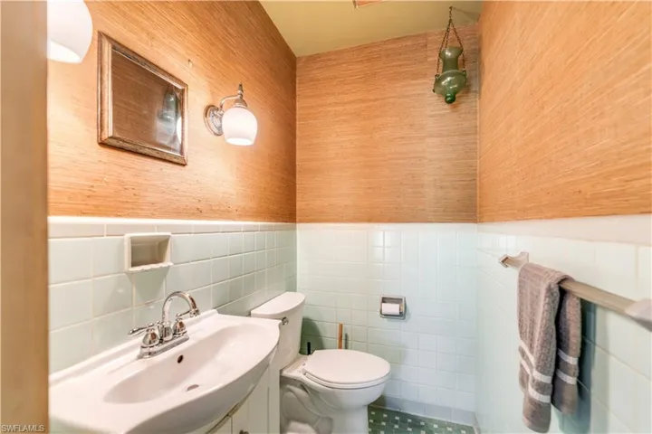 Bathroom featuring tile flooring, tile walls, tasteful backsplash, vanity, and toilet