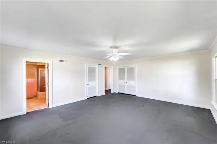 Unfurnished bedroom with ensuite bathroom, ceiling fan, and crown molding