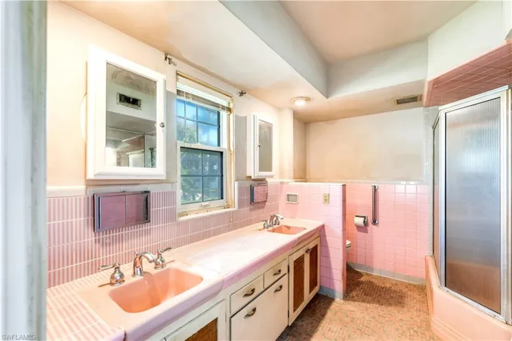 Bathroom featuring tile walls, tile flooring, dual sinks, and vanity with extensive cabinet space