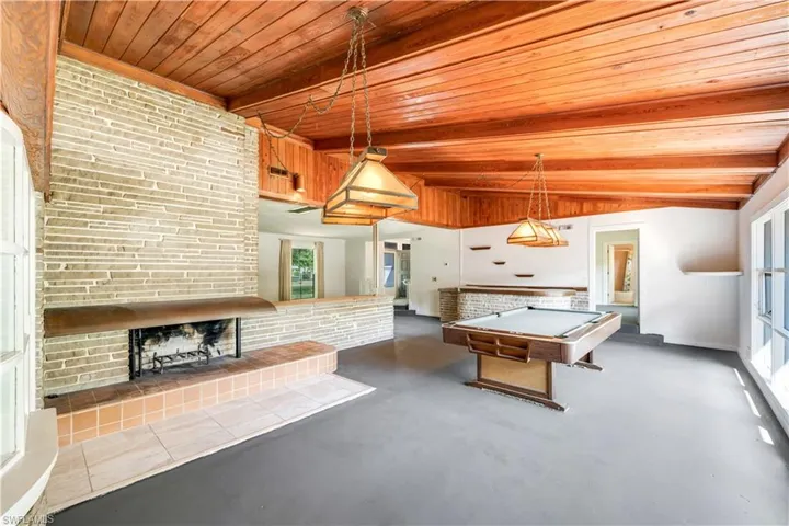 Game room with wooden ceiling, lofted ceiling with beams, a brick fireplace, and billiards