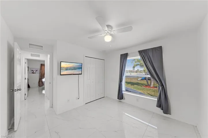 Unfurnished bedroom with ceiling fan, a closet, and light marble finish flooring