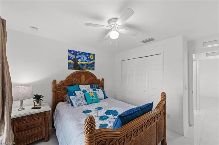 Bedroom featuring ceiling fan, a closet, and light marble finish flooring