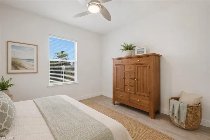 Bedroom featuring a ceiling fan, window with horizontal blinds, and wood-finish flooring