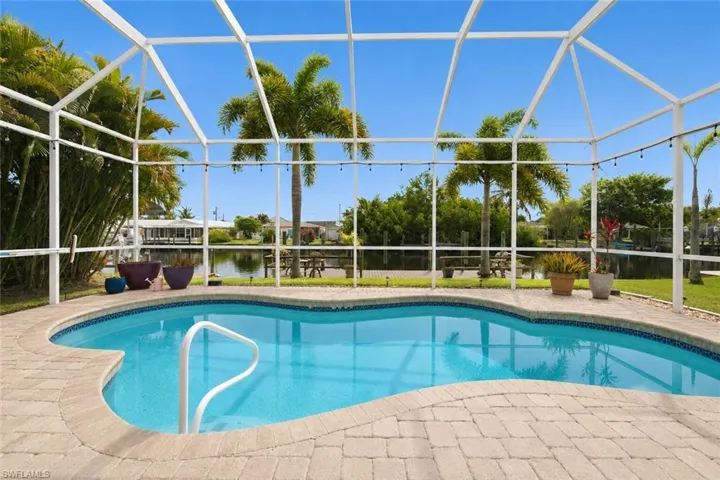 Screened outdoor pool area featuring a freeform pool with light blue interior finish and tile trim