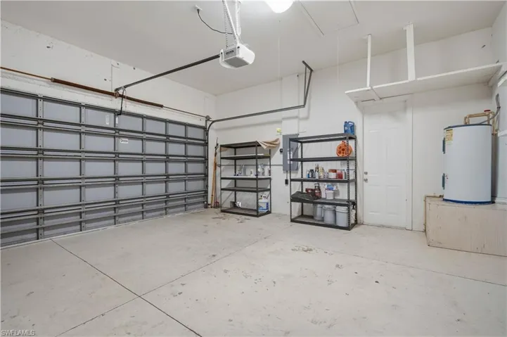 Spacious garage featuring a sectional overhead door, concrete flooring, overhead lighting, and built-in shelving
