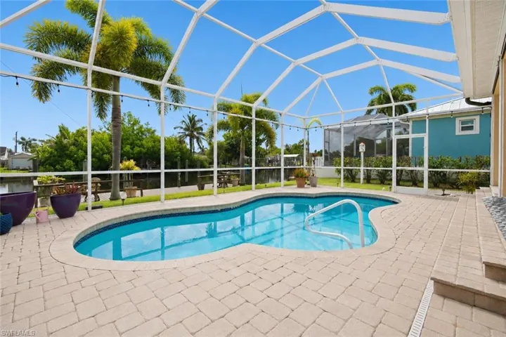 Screened lanai featuring a freeform swimming pool with integrated steps and a handrail