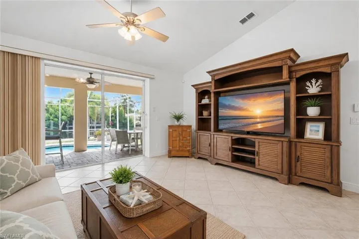 Living area featuring a spacious entertainment center with built-in shelving and cabinetry, vaulted ceiling, and ceiling fan