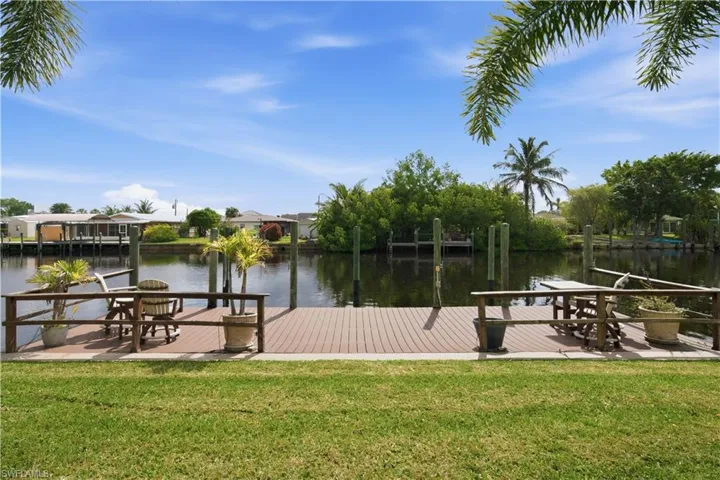 Waterfront dock with composite decking, surrounded by lush green lawn and tropical foliage