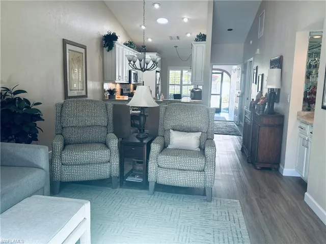 Living room with a notable chandelier, dark hardwood / wood-style flooring, and high vaulted ceiling