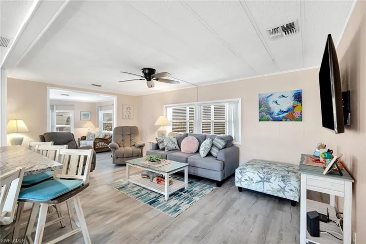 Open living room with abundant natural light, coastal finishes, and seamless flow into the kitchen and dining areas.